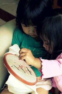 Two young children working on a cross stitch together