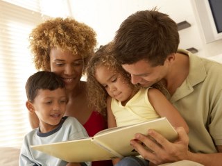 Two adults and two children reading together.