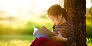 Child reading outside in nature