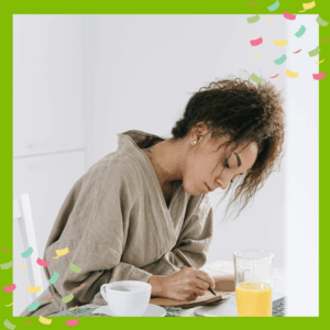 Person journalling in the morning at a table with coffee and orange juice