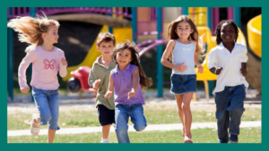 Group of 5 smiling children running on grass with playground in the background