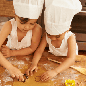 Budget birthday parties: two kids in chef hats, using cookie cutters in dough