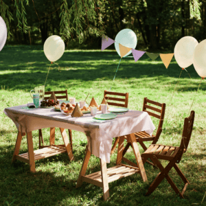 Outdoor picnic table with simple decor of balloons, banner, tablecloth